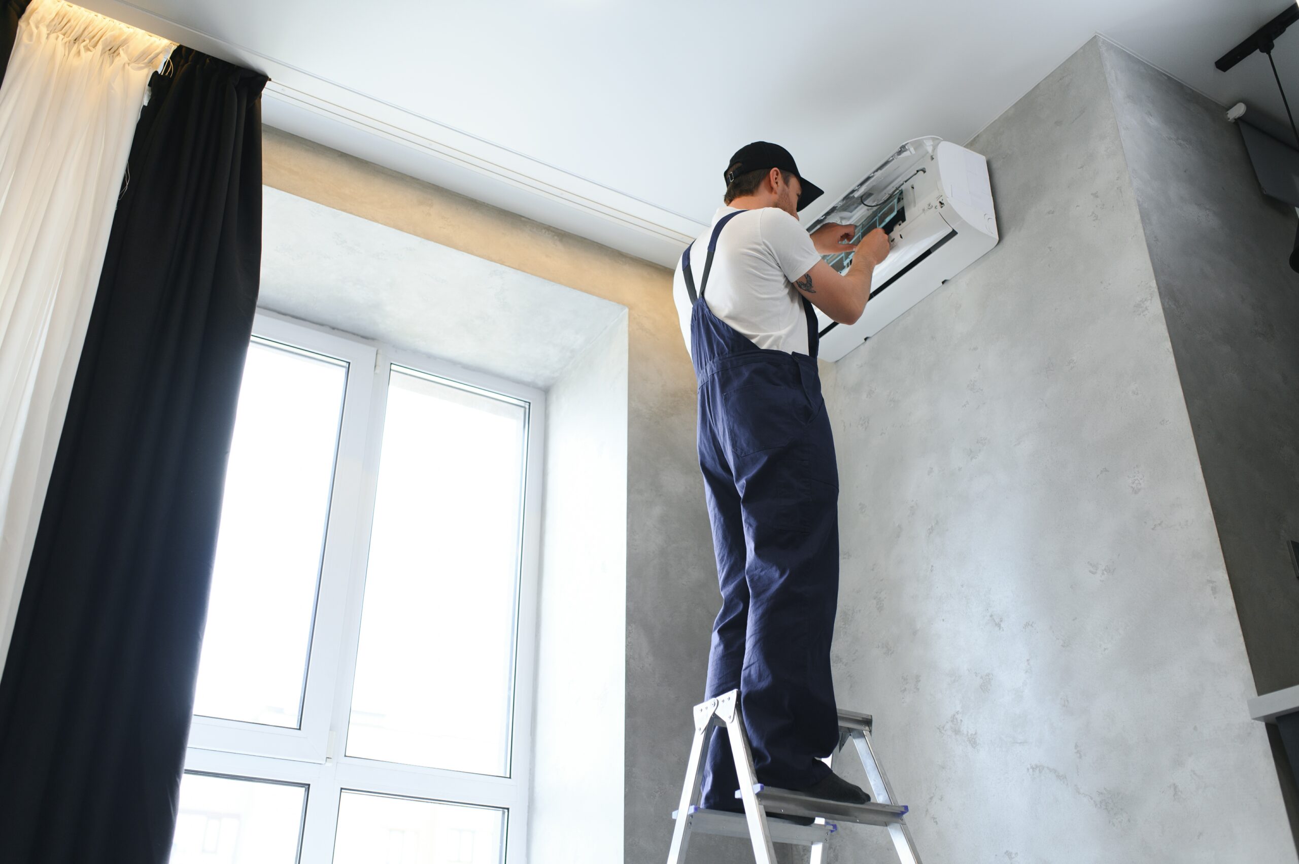 smiling young male electrician repair conditioner scaled